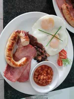 a plate of breakfast food with bacon beans beans and eggs at Dilisca Guesthouse in Durbanville