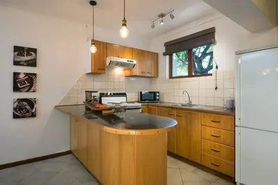 a kitchen with wooden cabinets and a white refrigerator at Just Unwind in Somerset West