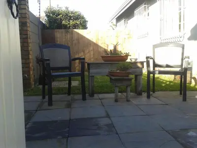 a patio with two chairs and a table with a potted plant at brookdale house in Cape Town