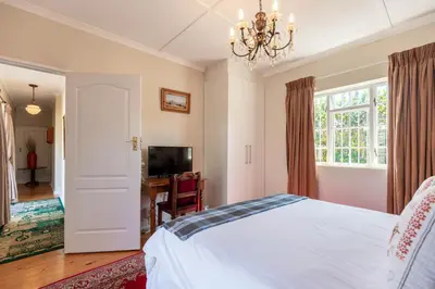 a bedroom with a bed and a television and a chandelier at brookdale house in Cape Town