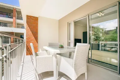 a patio with a table and chairs on a balcony at Superior Apartment Mayfair in Cape Town