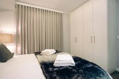 a bedroom with a large bed with white cabinets at Superior Apartment Mayfair in Cape Town