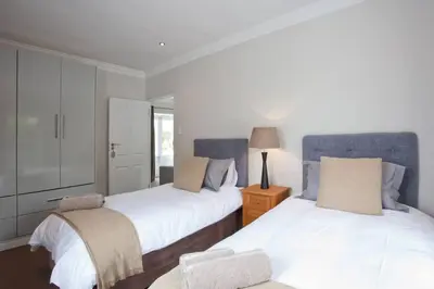 a bedroom with two beds and a table with a lamp at Anesta House in Stellenbosch
