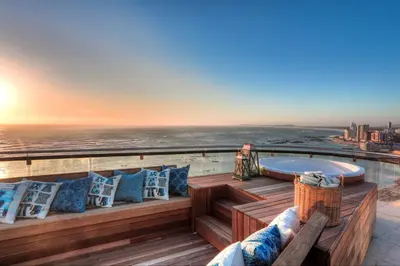 a deck with a hot tub and pillows at Ocean View Penthouse in Strand