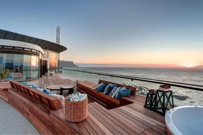 a deck with a couch and chairs on the beach at Ocean View Penthouse in Strand