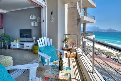 a room with a balcony with a view of the ocean at Portico 802 in Bloubergstrand