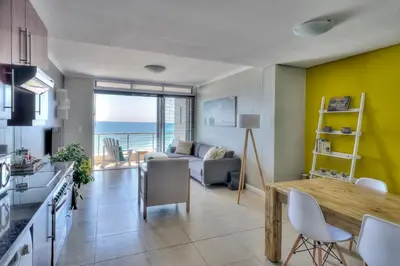a kitchen and living room with a view of the ocean at Portico 802 in Bloubergstrand