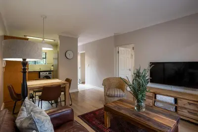 a living room with a television and a table at Vino Self Catering Apartment in Stellenbosch