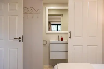 a bathroom with a white door and a sink at Vino Self Catering Apartment in Stellenbosch