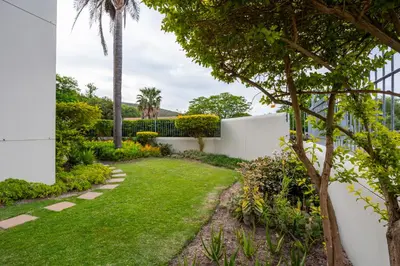 a garden with grass and trees and a fence at Vino Self Catering Apartment in Stellenbosch