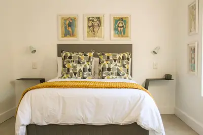 a bedroom with a bed and some pictures on the wall at Hermanus Champagne Accommodation in Hermanus