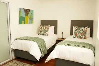 two beds in a room with white walls at Hermanus Champagne Accommodation in Hermanus