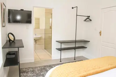 a bedroom with a bed and a shower and a television at Hermanus Champagne Accommodation in Hermanus
