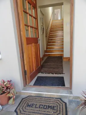 a hallway with a wooden door and stairs with a rug at The Mayflower in Hermanus