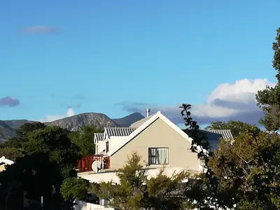a white house with mountains in the background at The Mayflower in Hermanus