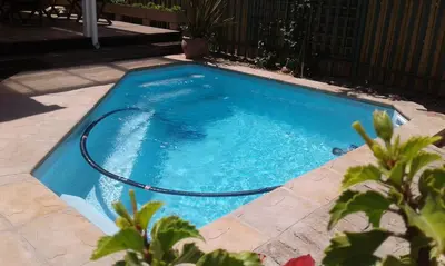 a swimming pool with a hose in a yard at The Mayflower in Hermanus