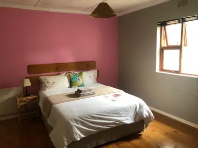 a bedroom with a bed and a pink wall at Inn On Highlands in Grabouw