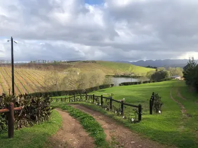 a dirt road in a field next to a fence at Inn On Highlands in Grabouw