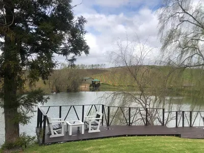 two chairs sitting on a dock on a lake at Inn On Highlands in Grabouw
