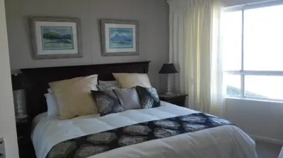 a bedroom with a bed with pillows and a window at Emerald Bay in Strand
