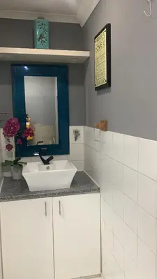 a bathroom with a white sink and a mirror at Mitchell's Guesthouse in Parow