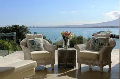two chairs and a table with a vase of flowers at 'The View' on Bikini Beach, Seafront, 2 bedroom, Sleeps 4 in Gordonʼs Bay