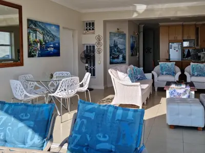a living room with white chairs and a table at 'The View' on Bikini Beach, Seafront, 2 bedroom, Sleeps 4 in Gordonʼs Bay