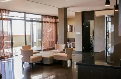 a living room with chairs and a table in a building at Manhattan Luxury Suite at Canal Walk in Cape Town