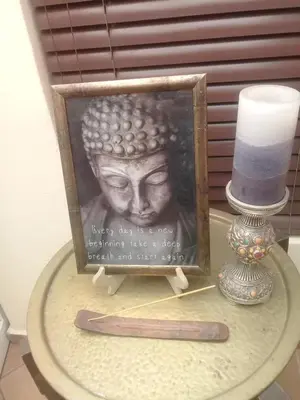 a picture of a statue on a table next to a candle at The Buddha Garden in Cape Town