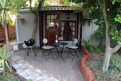 a patio with a table and chairs in front of a house at The Buddha Garden in Cape Town