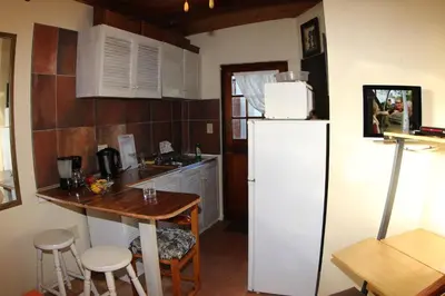 a kitchen with a white refrigerator and a table at The Buddha Garden in Cape Town