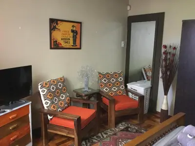 a living room with two chairs and a television at The Buddha Garden in Cape Town