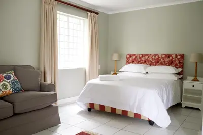 a bedroom with a large bed and a couch at Laurel Cottage in Franschhoek