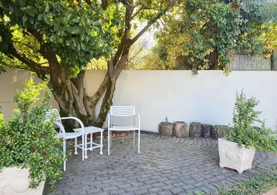 a patio with white chairs and a tree at Laurel Cottage in Franschhoek