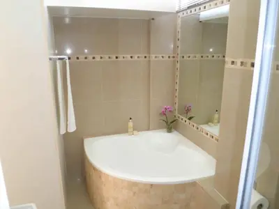 a bathroom with a bath tub and a mirror at 308 St Tropez in Strand