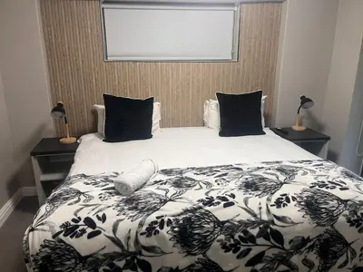 a bed with a black and white blanket and pillows at Du Kloof Lodge in Paarl