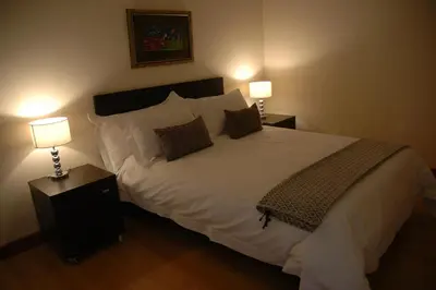 a bedroom with a large white bed with two lamps at Edelweiss Bed & Breakfast in Stellenbosch