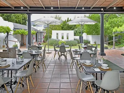 a patio with tables and chairs and umbrellas at Mont d'Or Franschhoek in Franschhoek