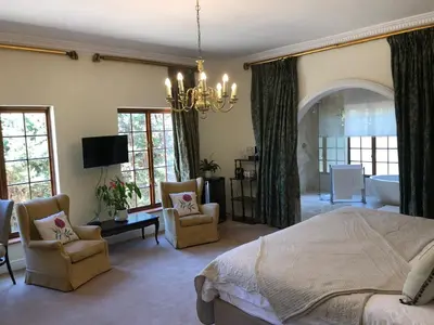 a bedroom with a bed and two chairs and a tub at Boutique Villa Guesthouse in Somerset West