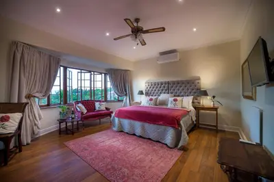 a bedroom with a bed and a ceiling fan at Boutique Villa Guesthouse in Somerset West