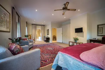 a bedroom with a bed and a couch and a tv at Boutique Villa Guesthouse in Somerset West