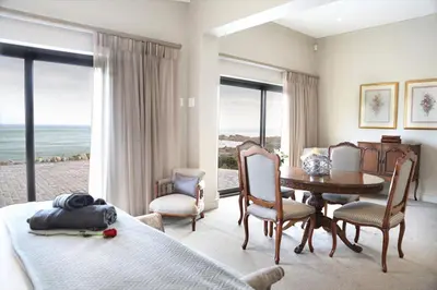 a bedroom with a bed and a table and chairs at Proteus Beach House in Rooiels