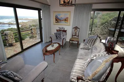 a living room with couches and chairs and large windows at Proteus Beach House in Rooiels
