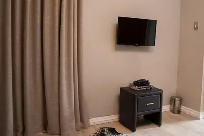 a room with a curtain and a television on a wall at A' Queenslin Guesthouse in Paarl