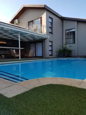 a large swimming pool in front of a house at A' Queenslin Guesthouse in Paarl
