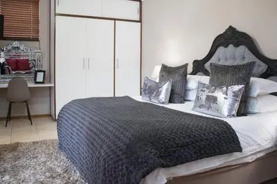 a bedroom with a black and white bed with pillows at A' Queenslin Guesthouse in Paarl