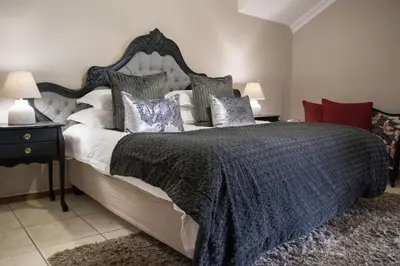 a bedroom with a large bed with a blue blanket and pillows at A' Queenslin Guesthouse in Paarl