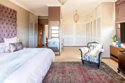 a bedroom with a large bed and a chair at A' Queenslin Guesthouse in Paarl