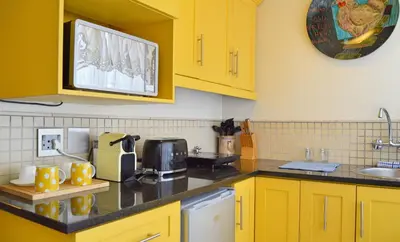 a kitchen with yellow cabinets and a black counter top at 1AA Wilhelmina Luxury Suites in Franschhoek