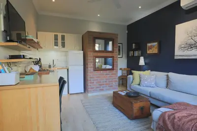 a living room with a blue couch and a kitchen at Treehouse at Theebos in Strand